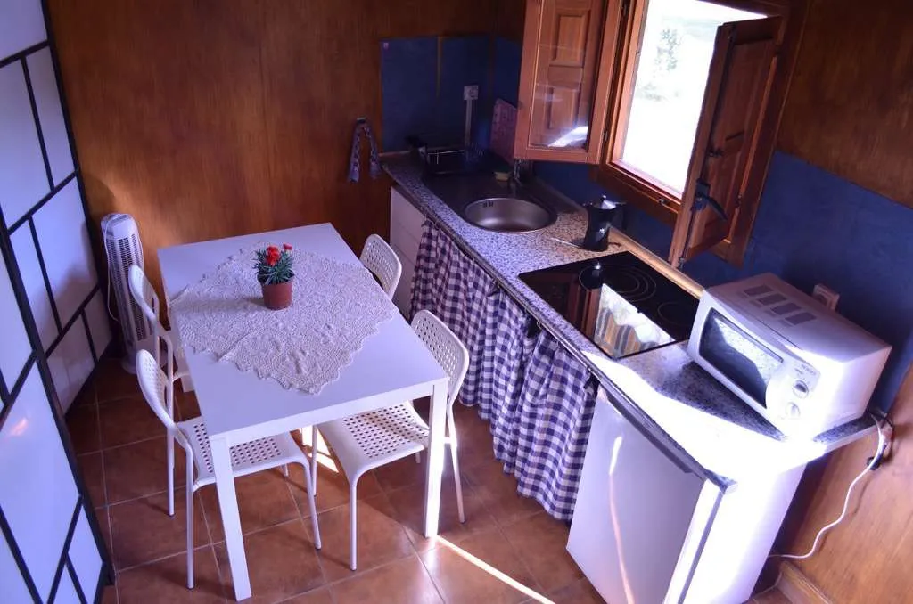 Cocina de la casita de madera con mesa, frigorífico y microondas
