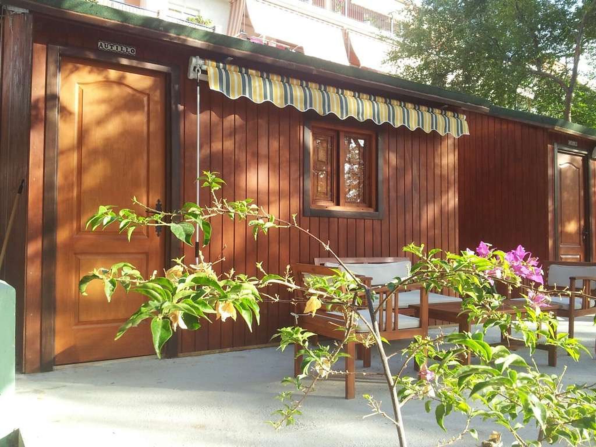 Fachada de la casita de madera con toldo y terraza